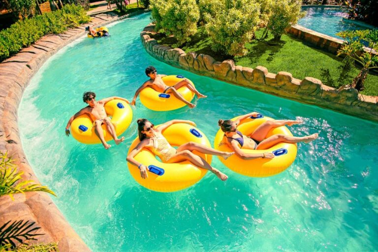 4 pessoas relaxando no Hot Beach Olímpia, dentro de uma piscina com boias amarelas em um dia de muito sol